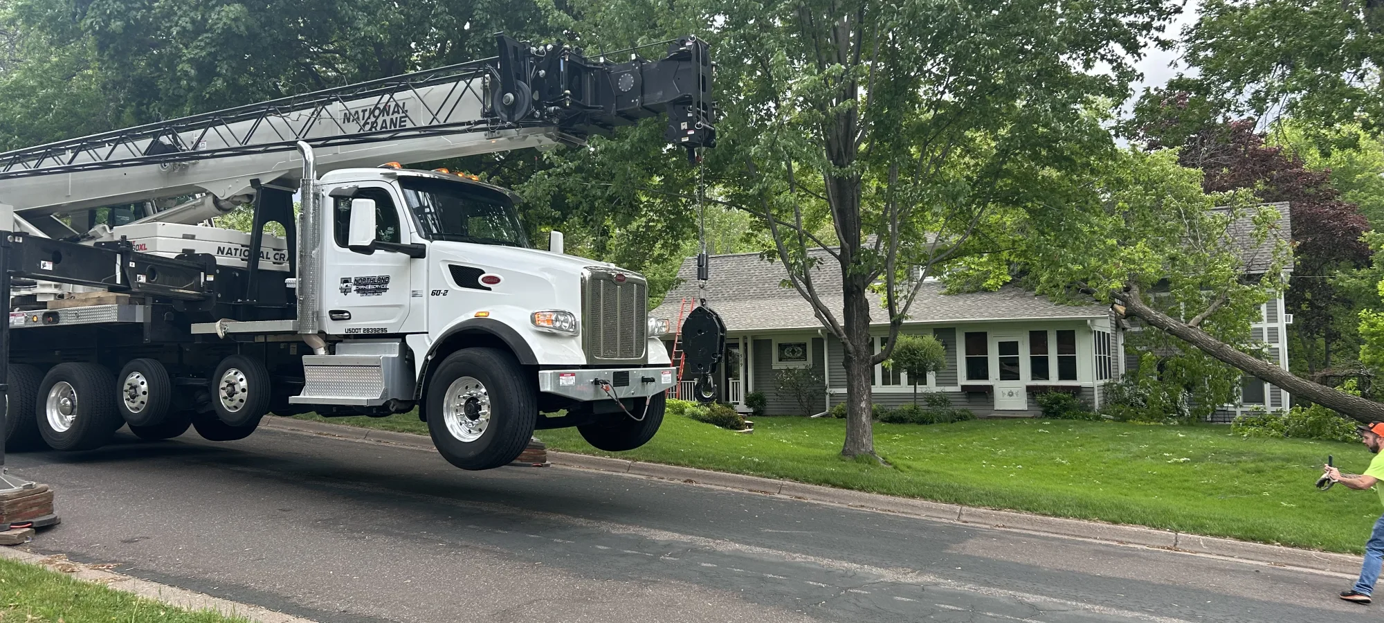 Crane truck lifting a tree during a residential tree removal